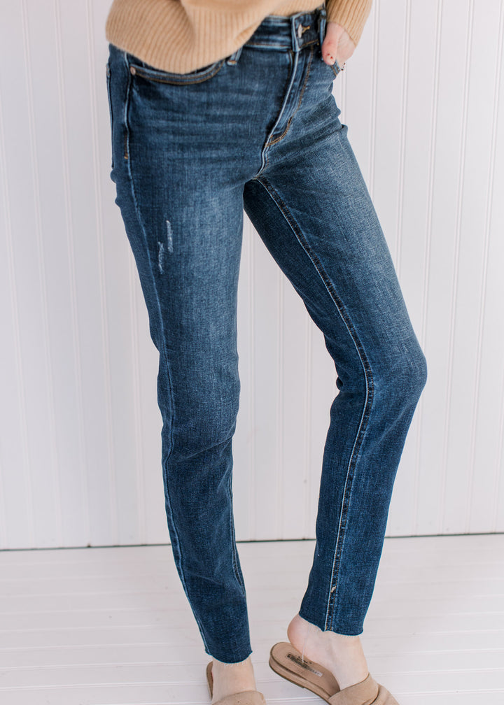 Model wearing a sweater with lightly distressed skinny jeans with a vintage wash and a raw hem.
