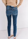 Back view of Model wearing lightly distressed skinny jeans with a vintage wash and a raw hemline.