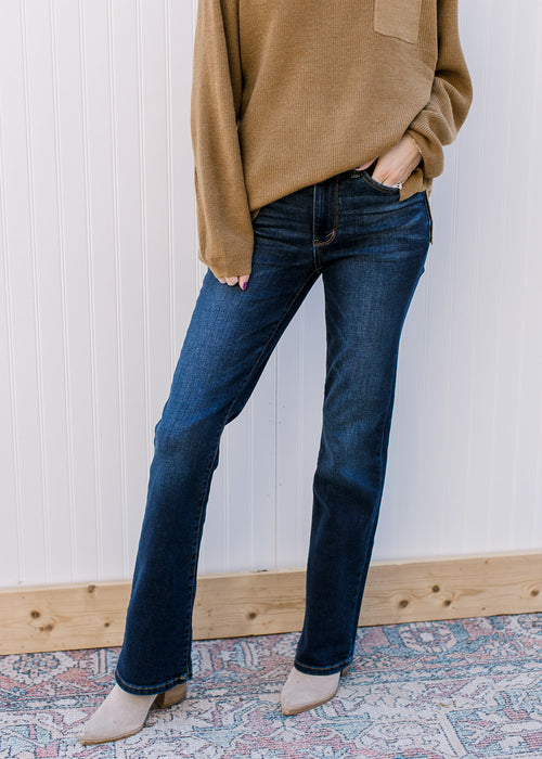 Model wearing booties with mid rise, dark wash jeans with a boot cut and stretchy fit. 