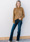 Model wearing a sweater and mid rise, dark wash jeans with a boot cut and stretchy fit. 