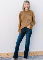 Model wearing a sweater and mid rise, dark wash jeans with a boot cut and stretchy fit. 