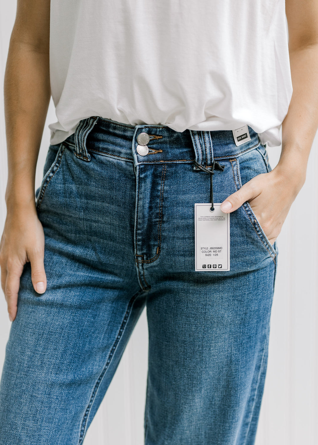 Close up of double button closure on a model in medium wash, wide leg jeans. 