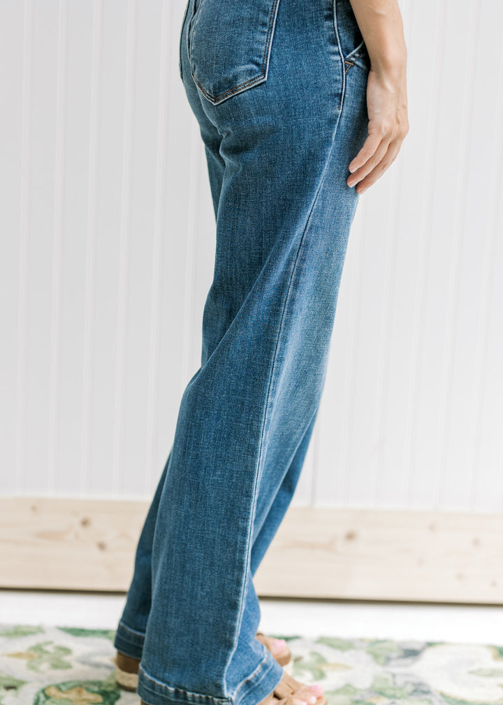 Side view of Model wearing medium wash wide leg jeans with a double button closure. 