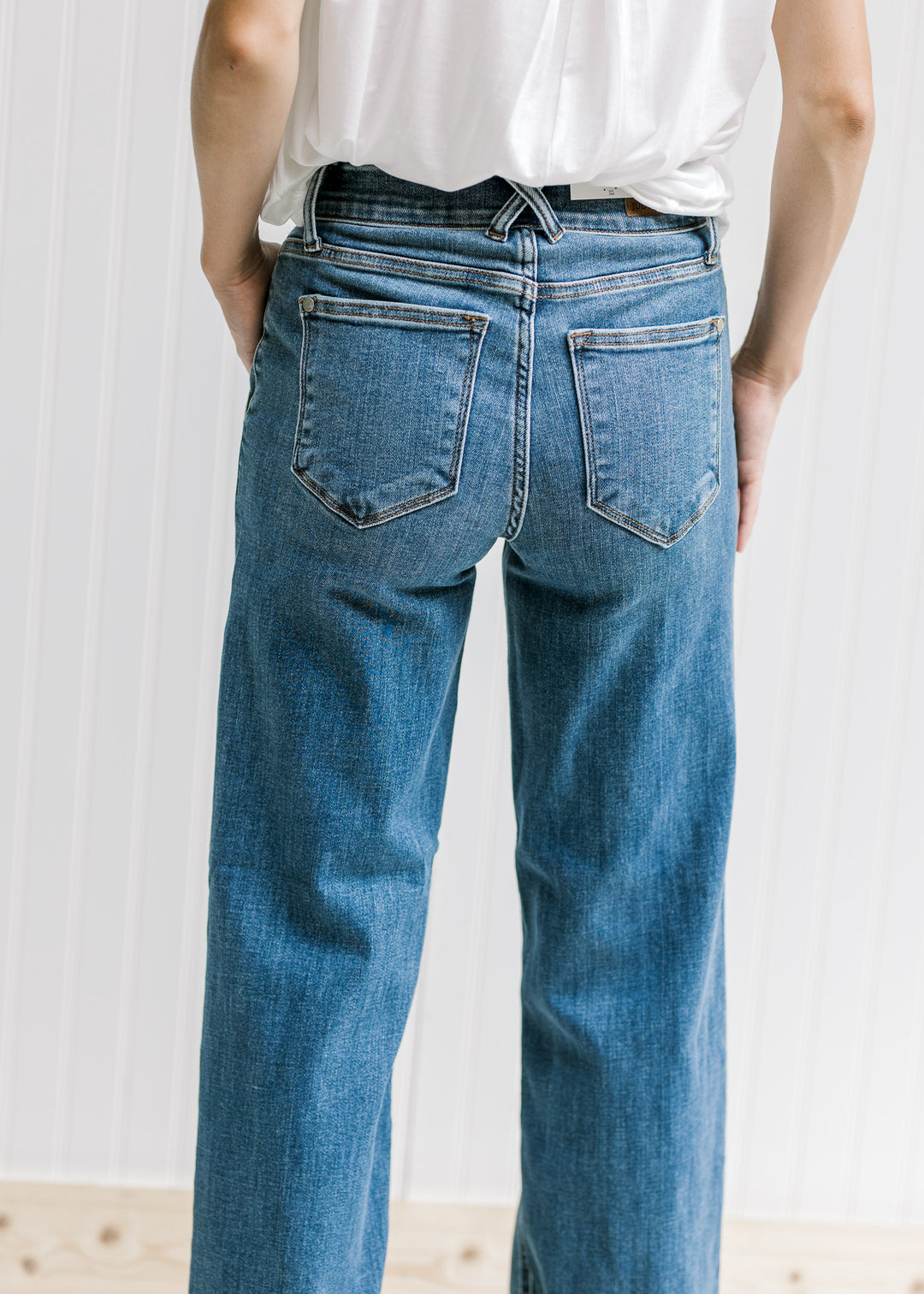 Back view of Model wearing medium wash wide leg jeans with a double button closure and wedges. 