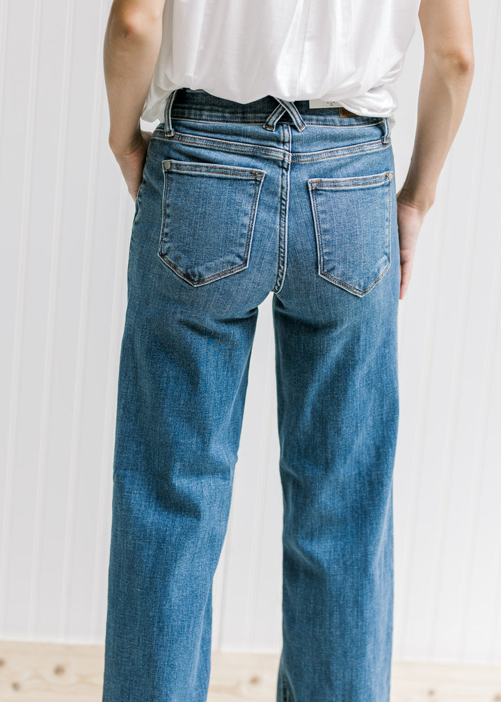 Back view of Model wearing medium wash wide leg jeans with a double button closure and wedges. 
