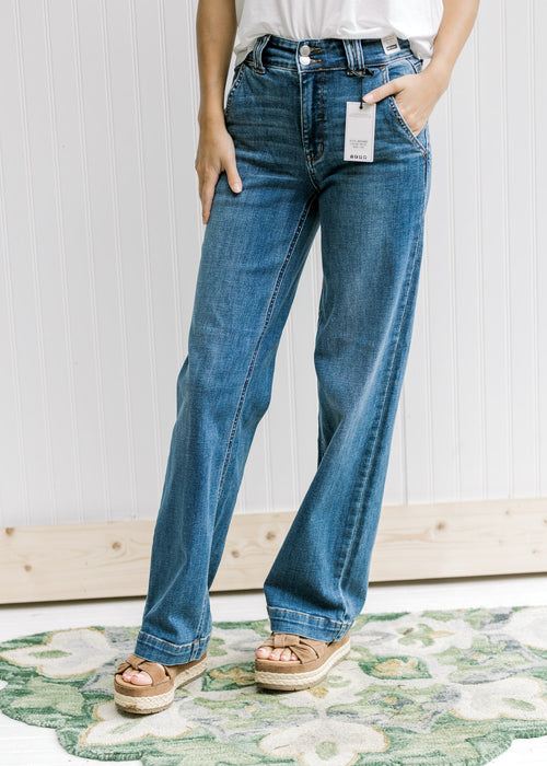 Model wearing medium wash wide leg jeans with a double button closure and wedges. 