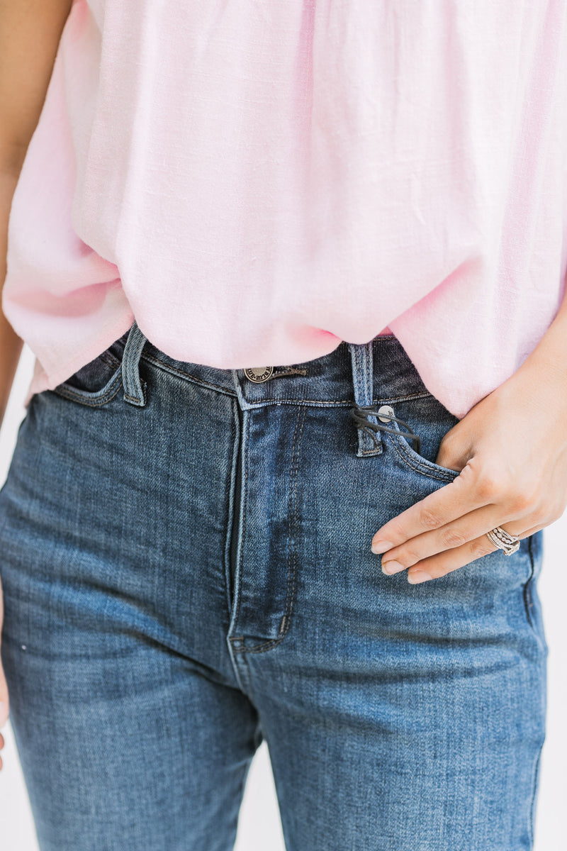 Close up of Model wearing a medium wash, hi waisted jean with a split hem and tummy control. 