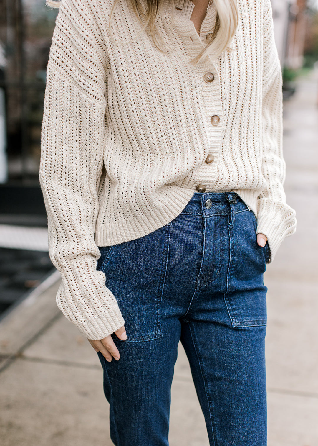 Close up on patch pockets and button front on dark jeans with slight flare leg fit. 