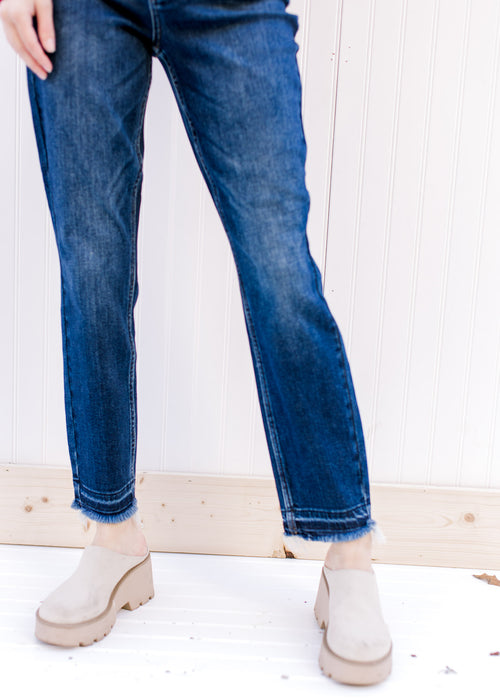 Model wearing dark wash jeans with a slim fit, high waist, tummy control and released hem. 