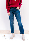 Model wearing a red sweater with dark wash jeans with a slim fit, high waist and released hem. 