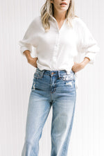 Model wearing a white top with light, hi waisted jeans that are worn at the back and front pocket