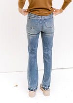 Back view of Model wearing medium wash jeans with a release hem, control top and a boot cut.