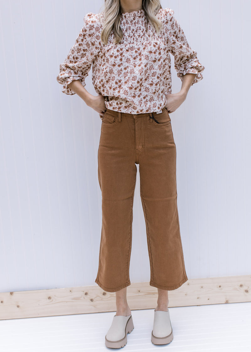 Model wearing a floral top and mules with camel pants with wide legs and tummy control. 
