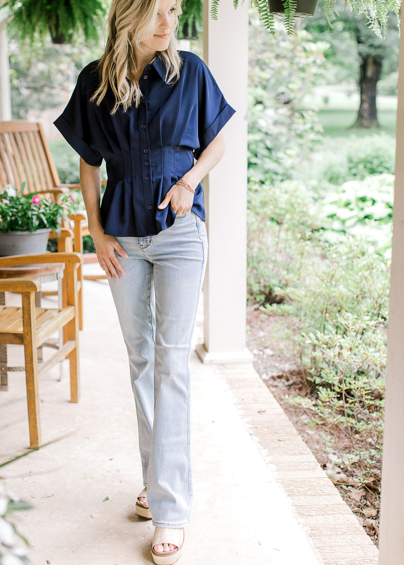Model wearing a blue top, wedges and light wash bootcut jeans with tummy control and a high waist.