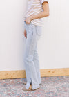 Side view of model wearing lightwash bootcut jeans with side slits and a built in tummy control. 