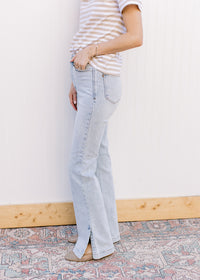 Side view of model wearing lightwash bootcut jeans with side slits and a built in tummy control. 