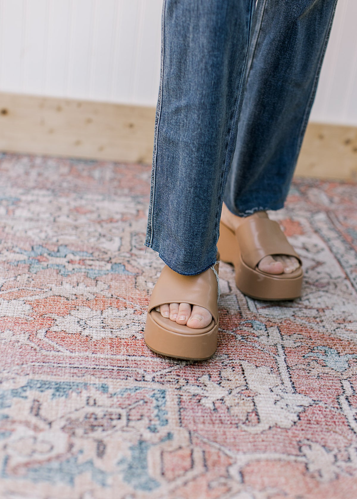 Close up of raw hem on medium wash jeans with a straight fit. 