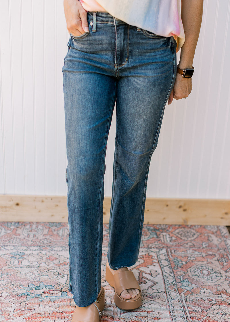 Model wearing Judy blue medium washed straight jeans with a raw hem.