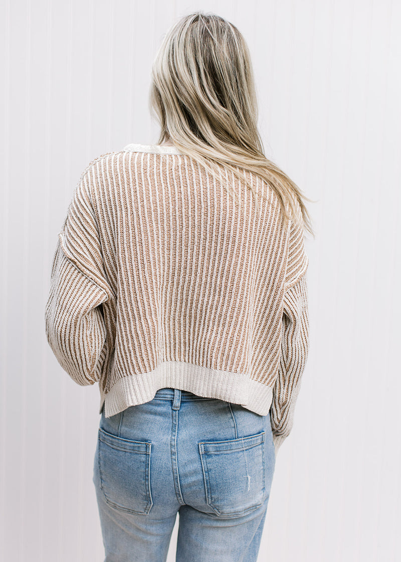 Back view of Model wearing a cream and tan striped sweater with long sleeves.