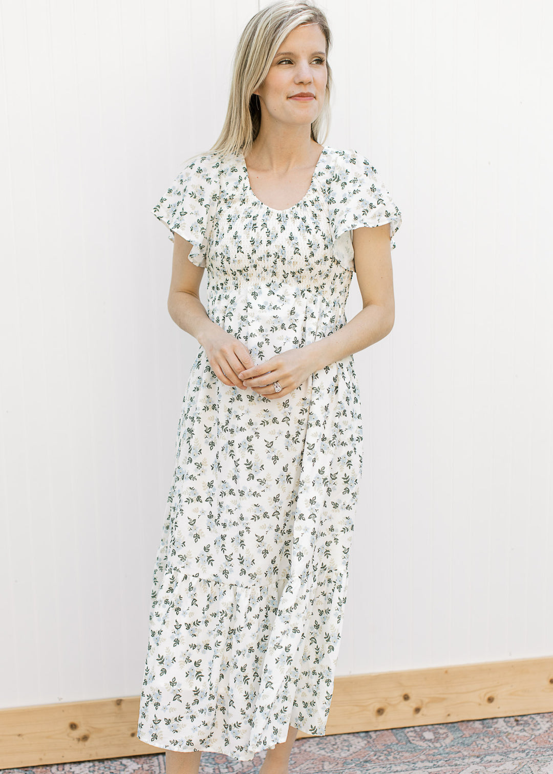 Model wearing an off white midi with floral, v-neckline, smocked bodice and flutter short sleeves.