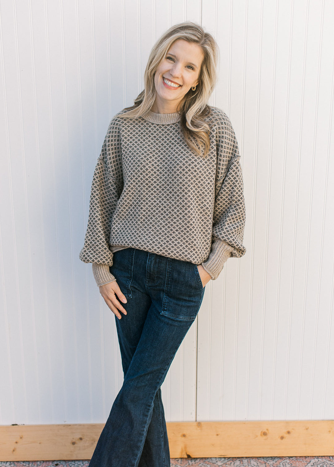 Model wearing jeans and a khaki sweater with a navy pattern with exposed seam accents.