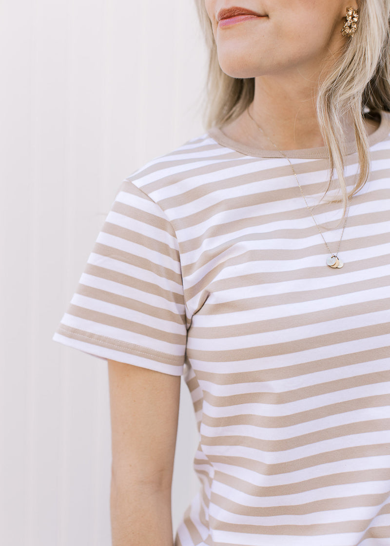 Close up of short sleeves and crew neck on a white tee with khaki stripes. 