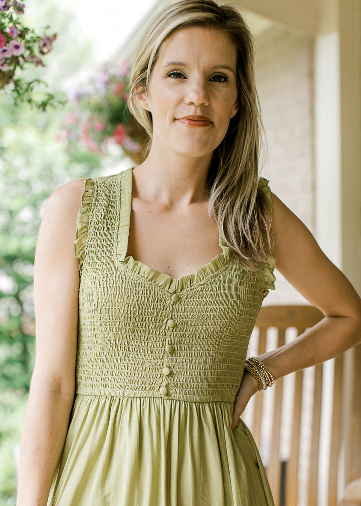Close up of smocked bodice and v-neck with faux buttons on a kiwi green midi dress. 