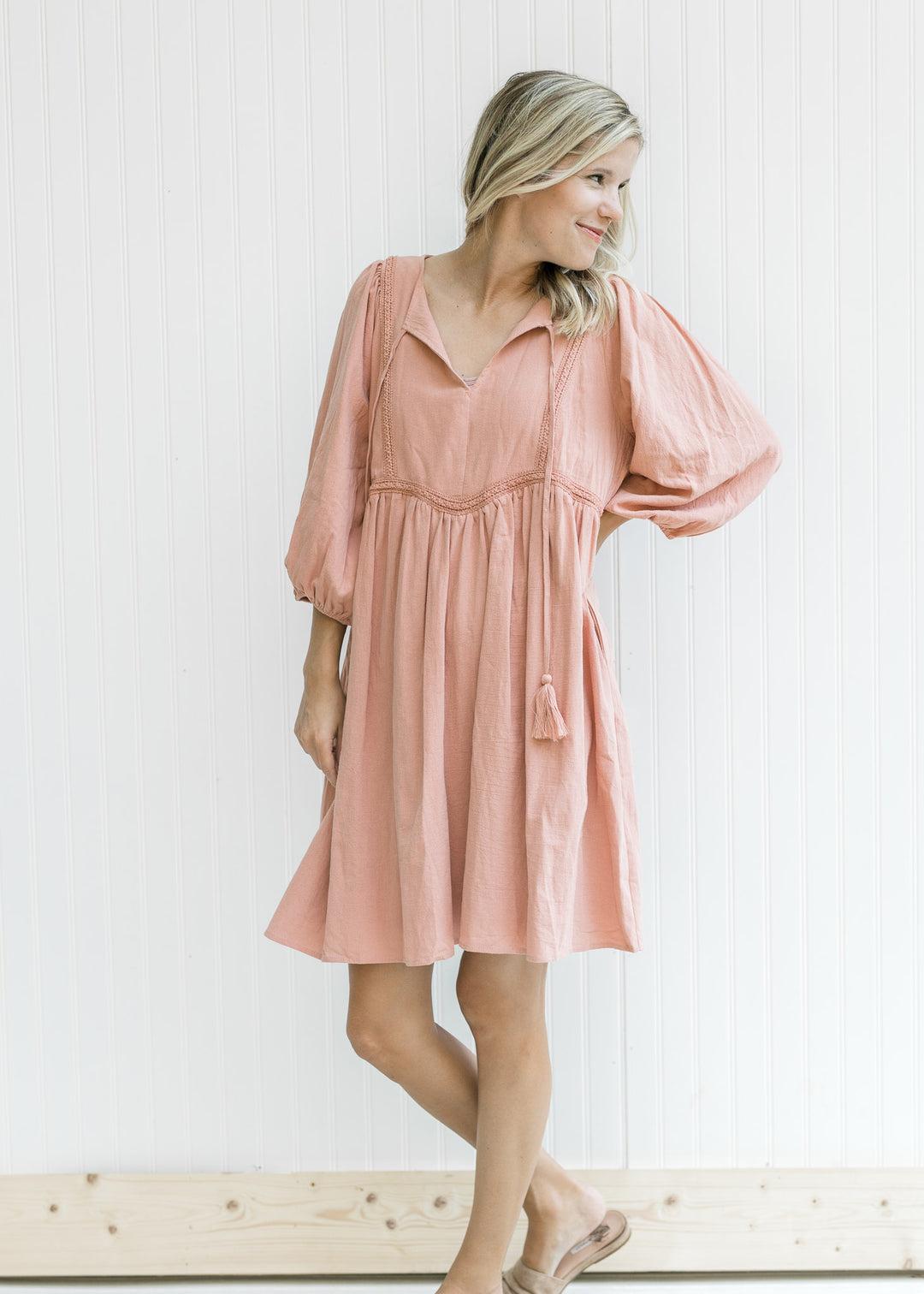 Model wearing a clay above the knee dress with embroidered detail, v-neck and 3/4 bubble sleeves. 