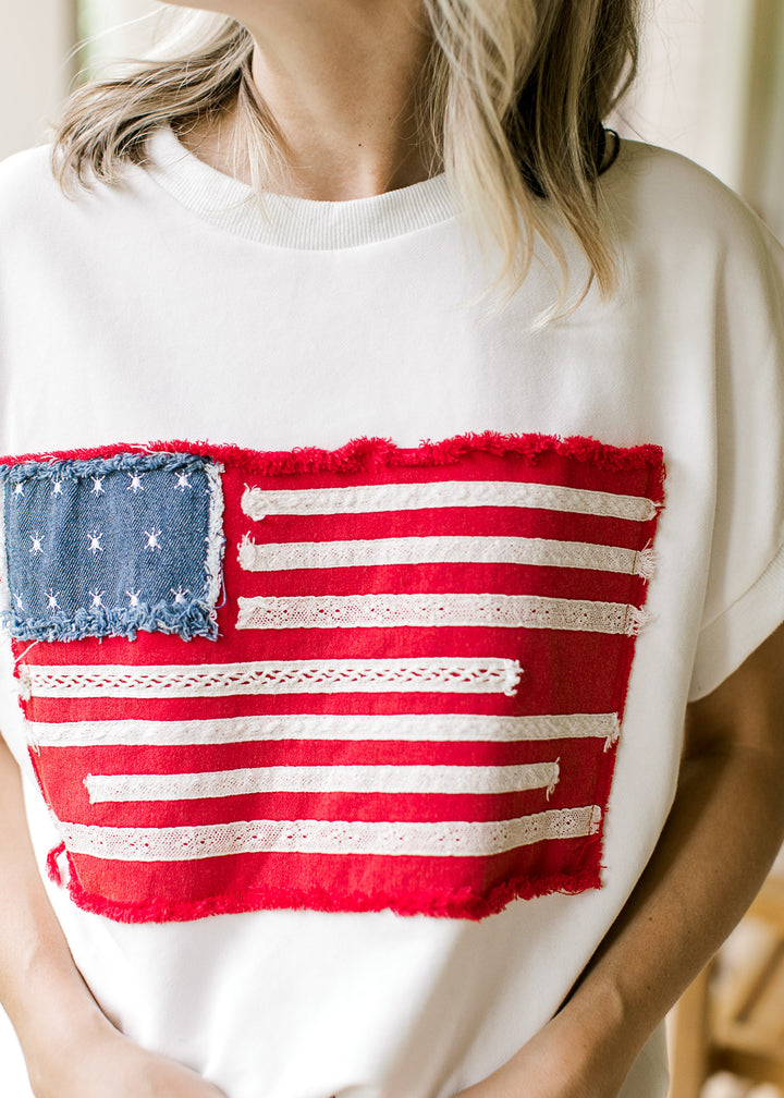 Close up of American flag with cream lace and denim with stars on a cream top with cap sleeve.