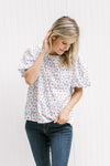 Model wearing a lavender top with a cream daisy pattern, crinkle material and short puff sleeves. 