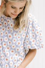Close up of short puff sleeves on a lavender top with a cream daisy pattern and crinkle material. 
