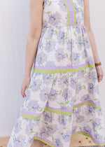 Close up of tiers with lavender and lime trim on a sleeveless cream maxi with floral. 