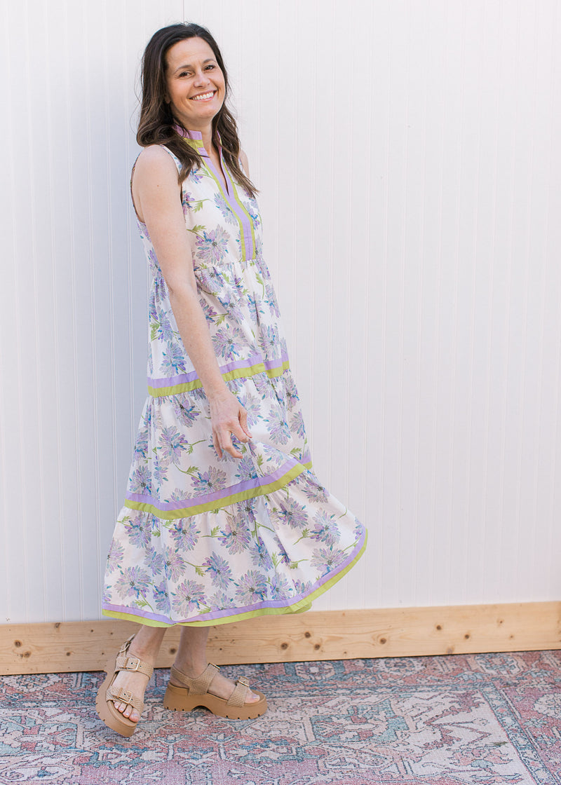 Model wearing sandals and a sleeveless cream maxi with lavender floral and a v-neck. 