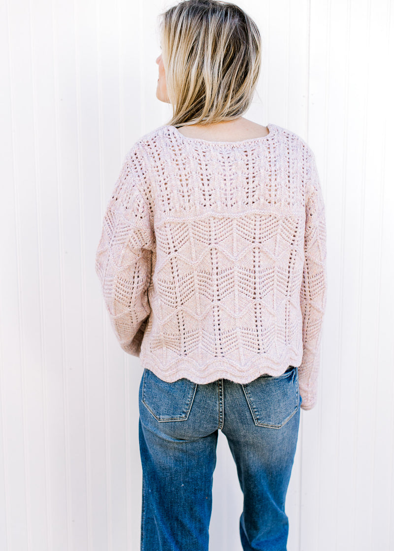 Back view of Model wearing a lavender sweater with open weave, scalloped hem and long sleeves.