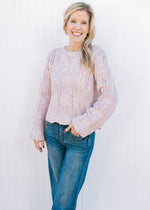 Model wearing jeans and a lavender sweater with scalloped hem and long sleeves.