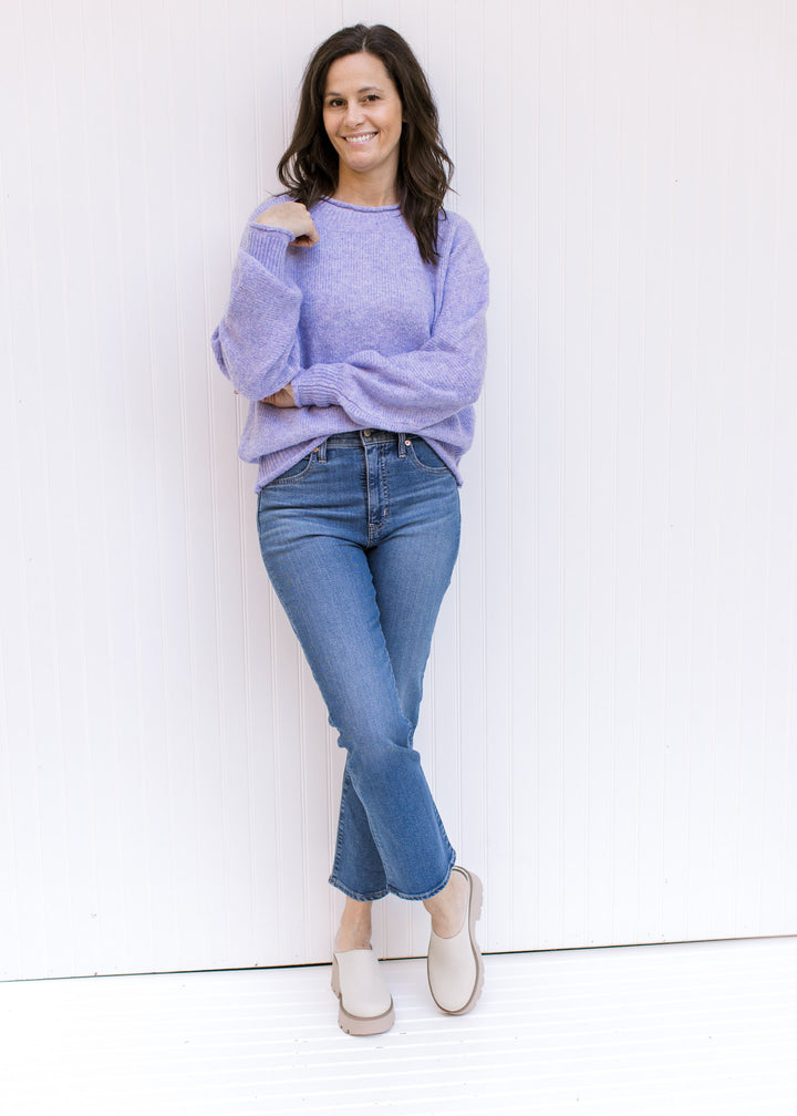 Model wearing a lavender knit sweater with long sleeves, rolled hems and a round neckline. 