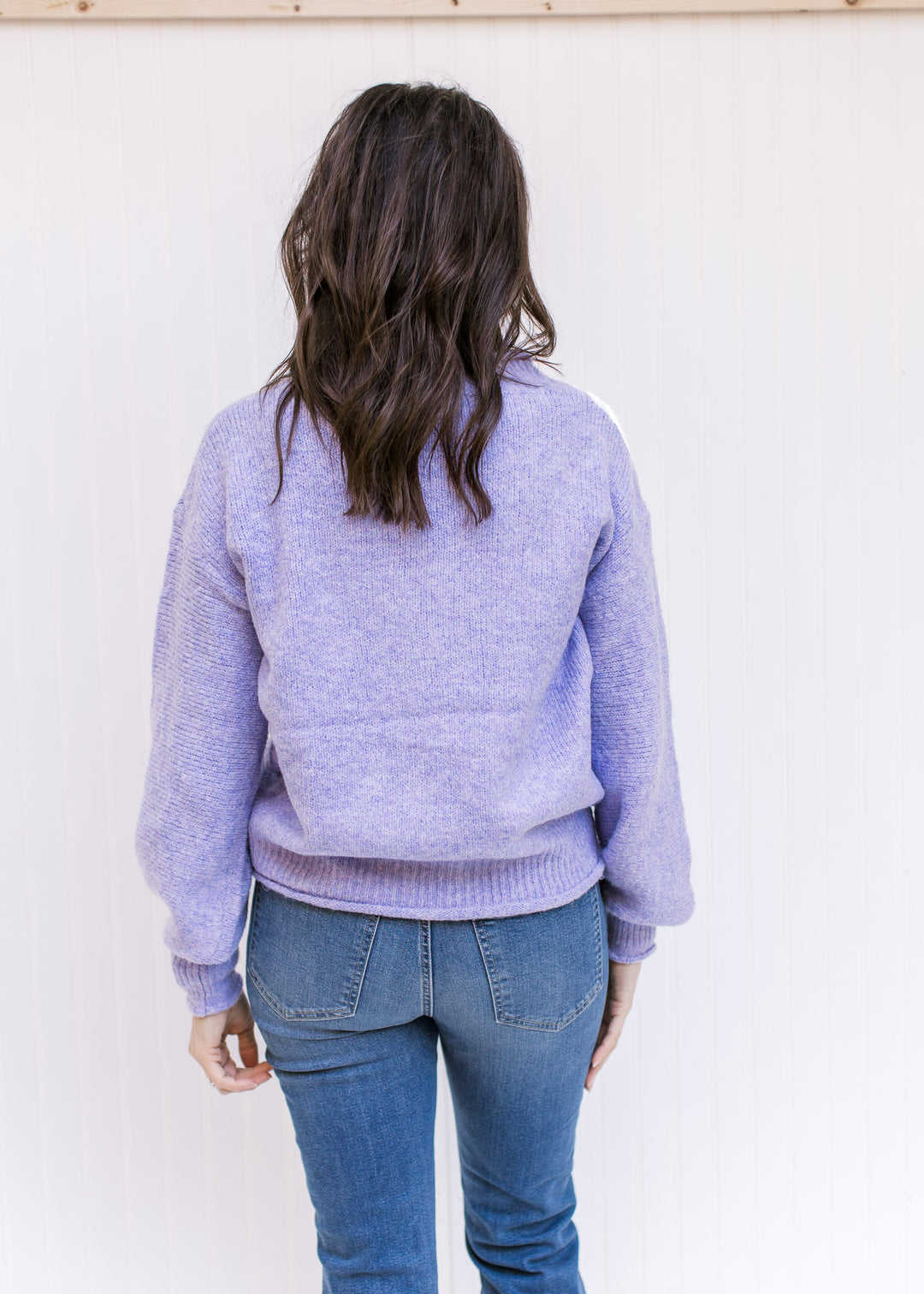 Back view of Model wearing a lavender knit sweater with long sleeves, rolled hems and a round neck. 