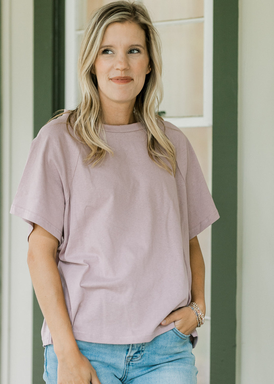 Model wearing jeans and a lavender tee with round neck, short sleeves and a loose fit. 
