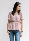Model wearing a lavender top with a cream floral pattern, elastic waistband and short sleeves. 