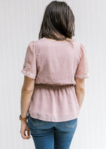 Back view of Model wearing a lavender top with a cream floral embroidery and flutter short sleeves. 