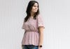 Model wearing a lavender short sleeve top with a cream embroidery and an elastic waistband. 