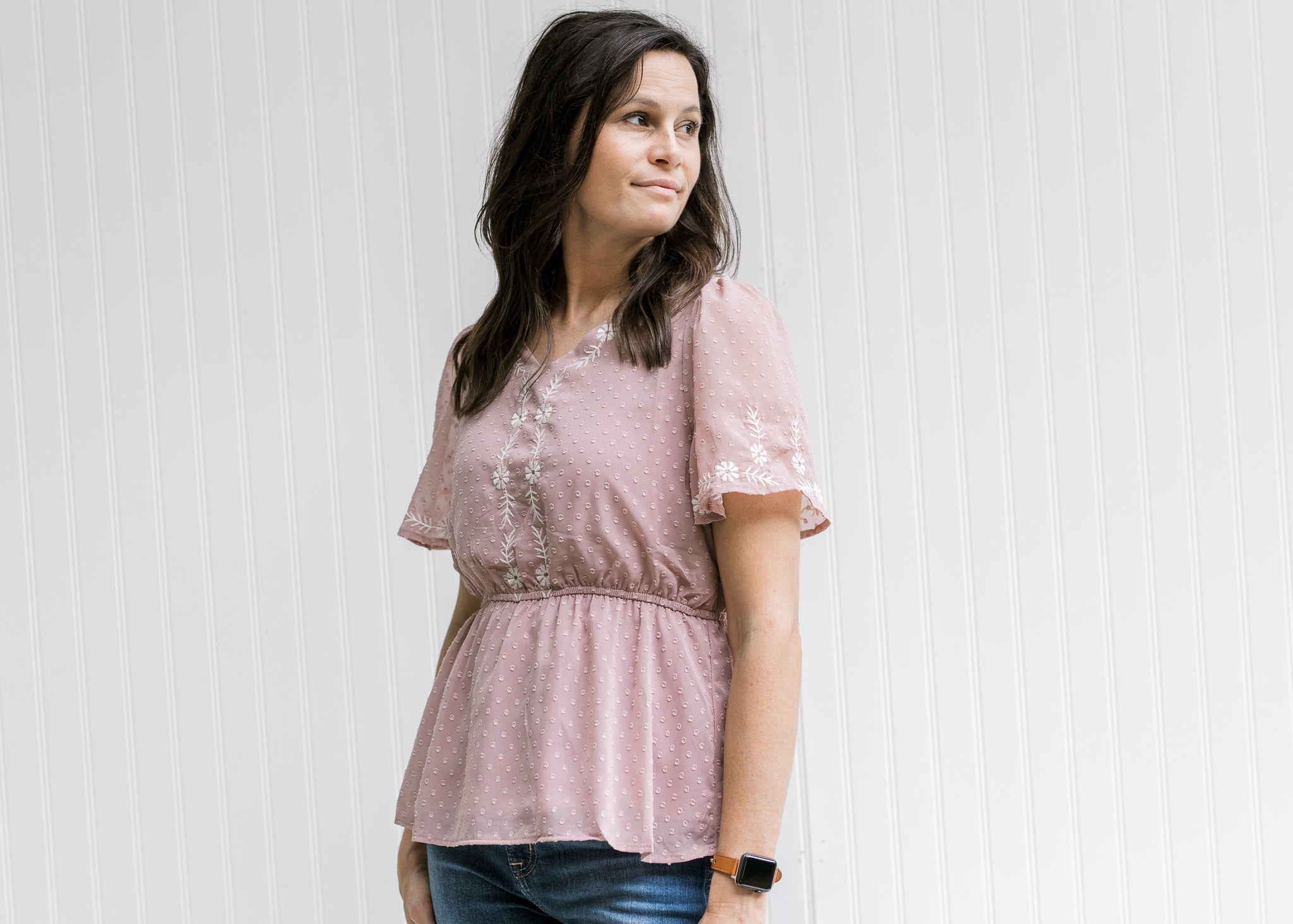 Model wearing a lavender short sleeve top with a cream embroidery and an elastic waistband. 