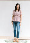 Model wearing jeans and sandals with a short sleeve lavender top with cream embroidered floral. 