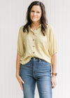 Model wearing jeans with a lemon grass colored button up top, with patch pockets and 3/4  sleeves. 