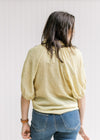 Back view of model wearing a lemon grass colored button up top, with patch pockets and 3/4  sleeves.