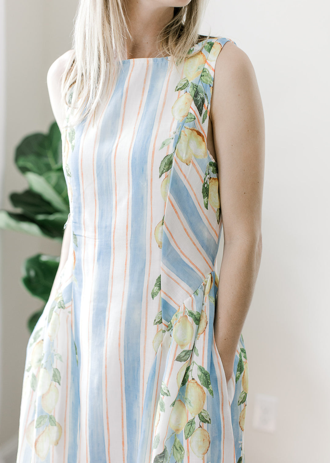 Model wearing a white and blue striped midi with lemon detail on the outside edge and pockets.
