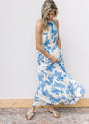 Model wearing sandals and a white maxi with light blue floral, an elastic waist and back tie.