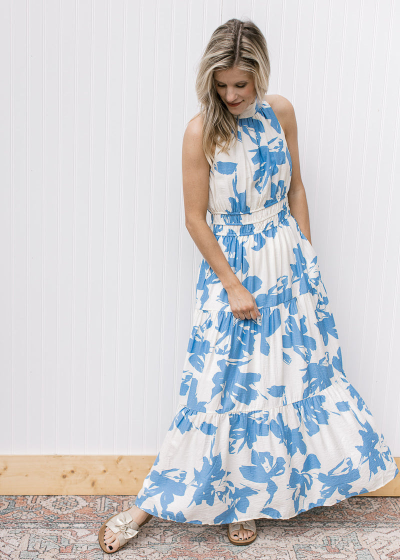 Model wearing a white maxi with light blue floral, an elastic waist and racer back with back tie.