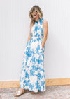 Model wearing a white maxi with light blue floral, pockets and racer back with back tie.