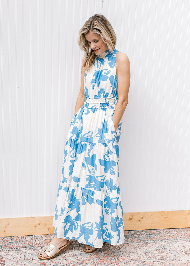 Model wearing a white maxi with light blue floral, pockets and racer back with back tie.